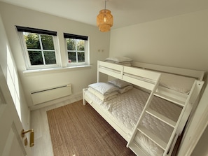 Ein Schlafzimmer mit einem Etagenbett, einem Fenster mit Jalousien, einem Heizkörper und einem Teppich.