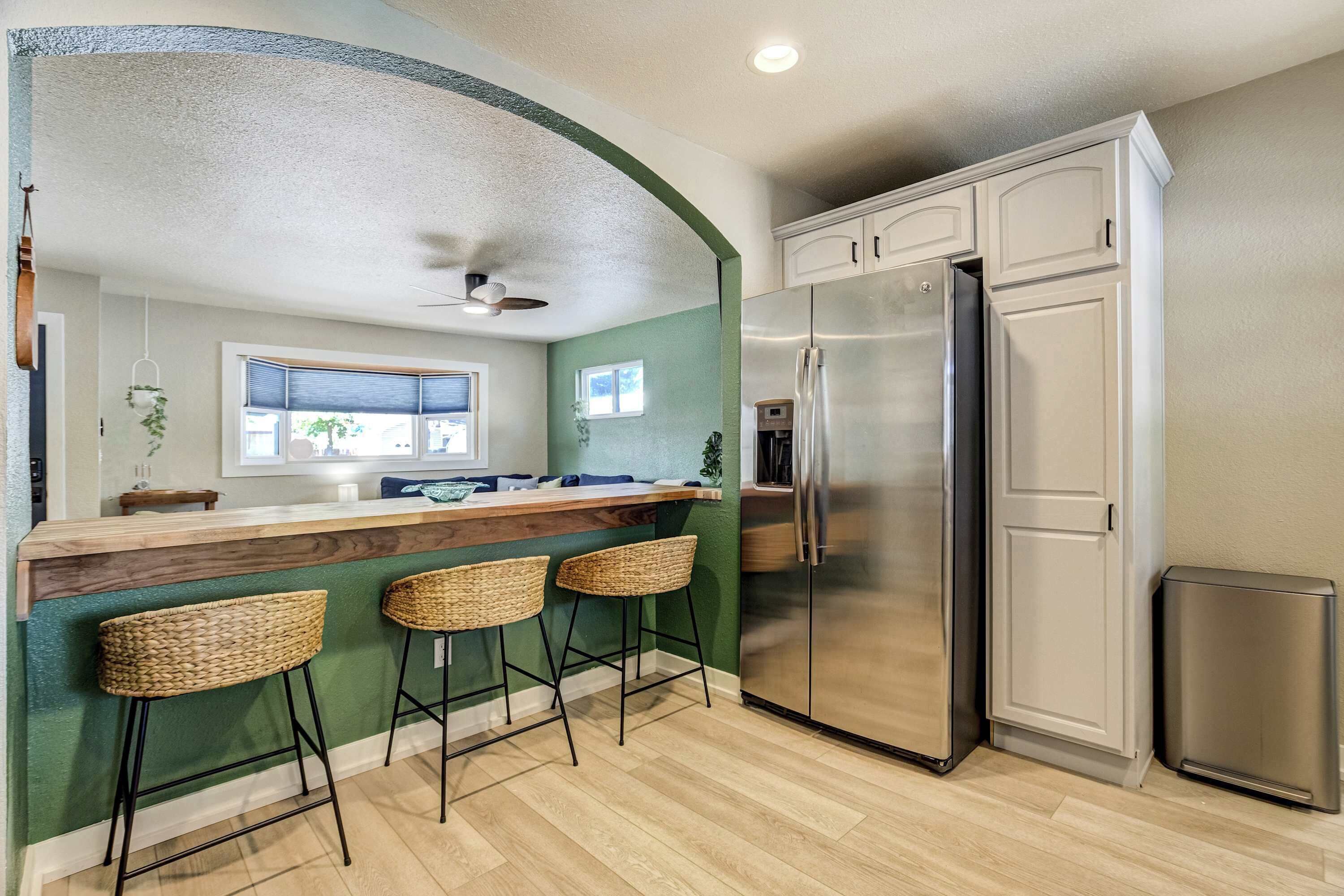 A kitchen with a bar area, a stainless steel refrigerator, and a trash can.