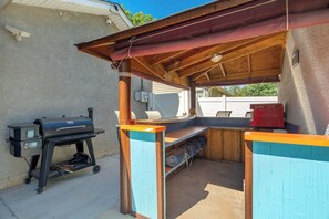 An outdoor barbecue area with a grill, a red grill, and a wooden structure with a roof. - Aloha Springs! Private Heated Pool & Hot Tub (Colorado Springs)