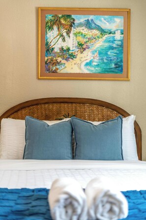 A bed with a woven headboard, two pillows, and a painting of a beach scene above it. - Aloha Springs! Private Heated Pool & Hot Tub (Colorado Springs)