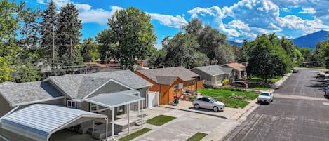 Una calle residencial con casas, un toldo para coche y un cielo azul despejado.