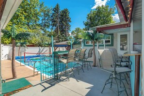 Ein Garten mit Swimmingpool, Sitzgelegenheit im Freien und einer überdachten Terrassenfläche.