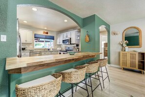 A kitchen with a bar area, bar stools, and a microwave. - Aloha Springs! Private Heated Pool & Hot Tub (Colorado Springs)