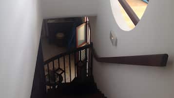 A staircase with a handrail and a circular window on the wall.