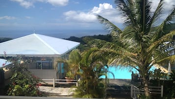 A building with a white roof, a pool, and palm trees.