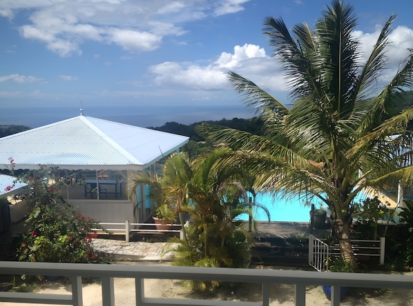 A building with a white roof, a pool, and palm trees.