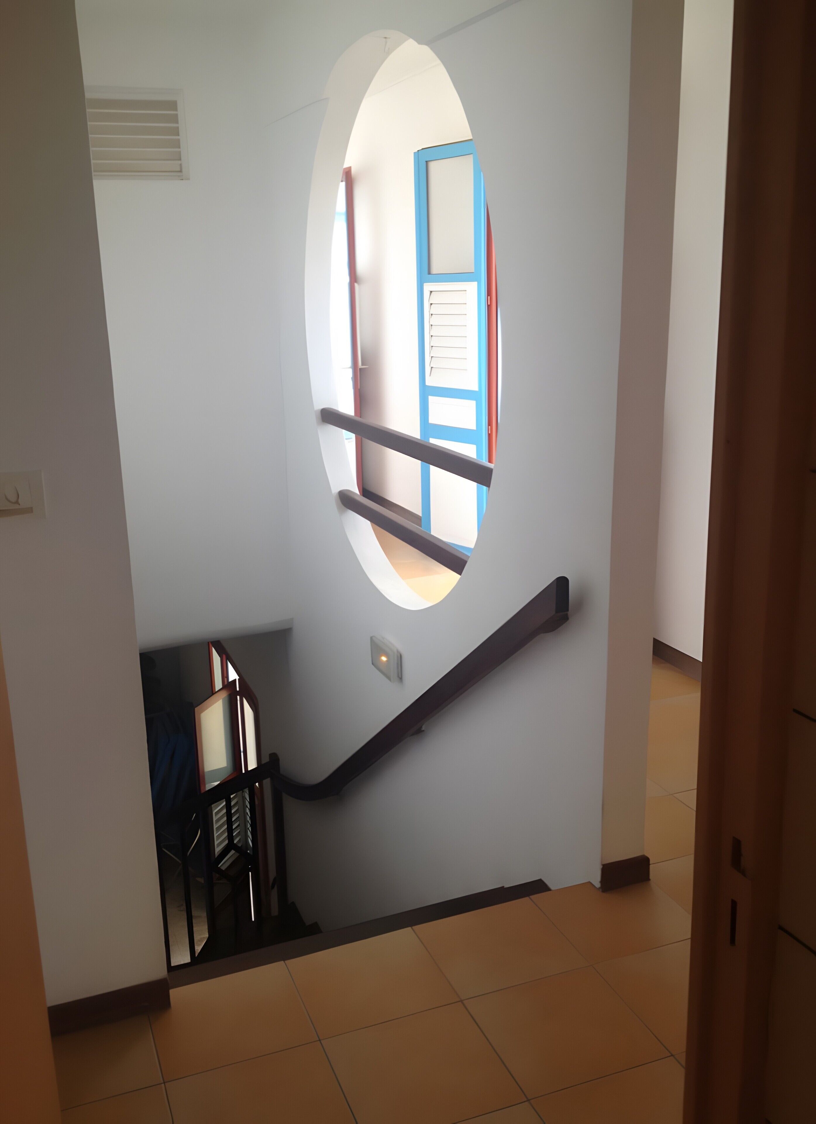 A staircase with a handrail, a door with a blue frame, and a small window.
