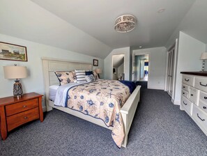 A bedroom with a bed, nightstand, dresser, and a ceiling light fixture. - Luxury Coastal Apt Above Bakery,Near Beach, Acadia (Hancock)