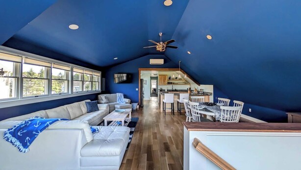 Um amplo loft com teto alto, área de jantar e sala de estar com sofá e cadeiras.