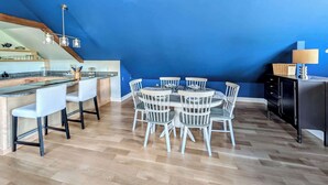 Uma cozinha moderna com teto azul, soalho de madeira e um espaço de refeições com cadeiras brancas.