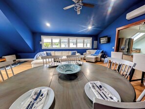 A dining area with a round table, chairs, and a central decorative bowl. - Luxury Coastal Apt Above Bakery,Near Beach, Acadia (Hancock)