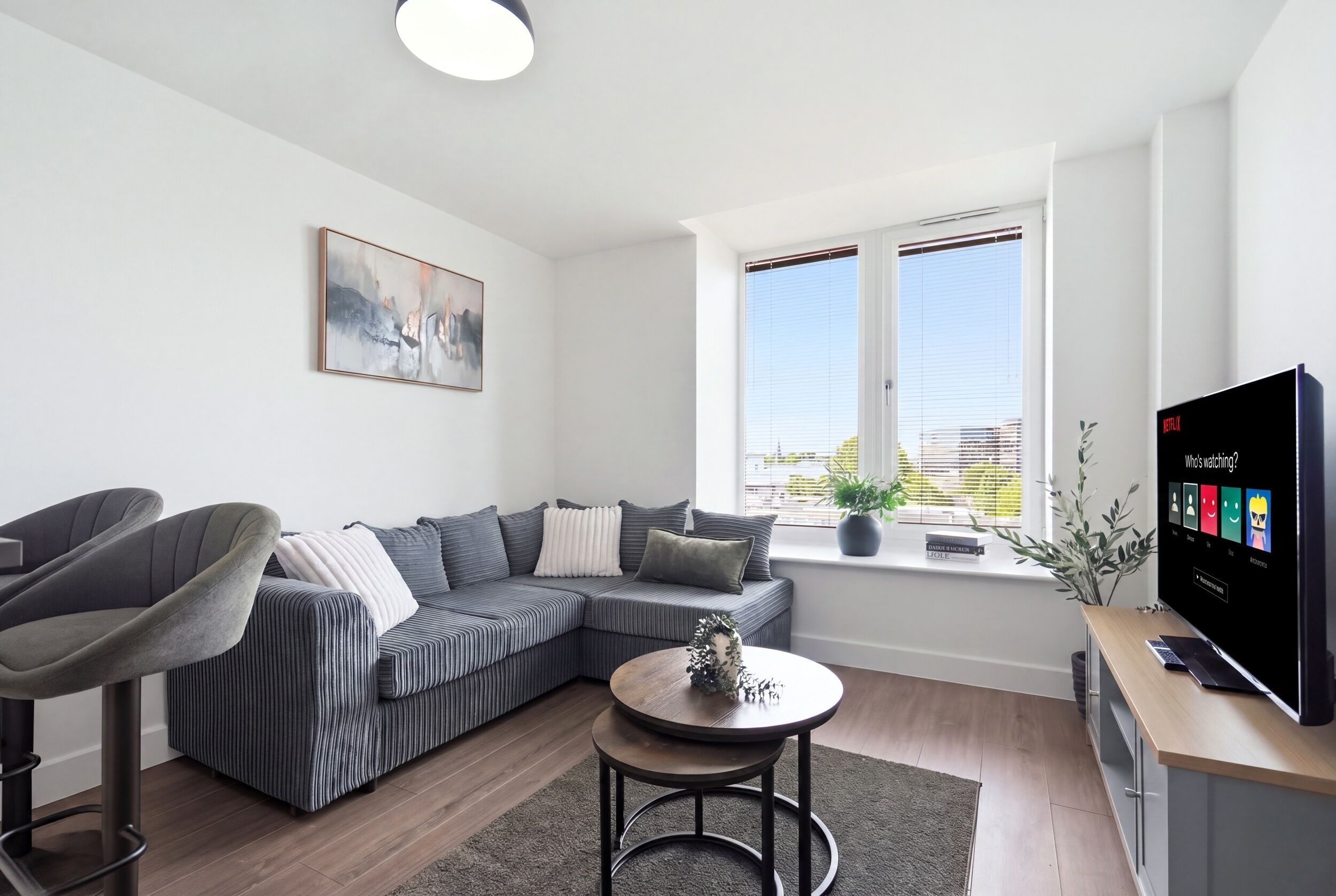 Ein modernes Wohnzimmer mit einem Ecksofa, einem runden Couchtisch und einem Flachbildfernseher.