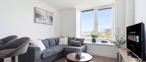 A modern living room with a sectional sofa, a round coffee table, and a flat-screen TV.