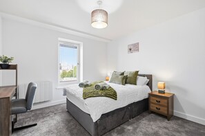 A bedroom with a bed, bedside table, lamp, window, radiator, and a chair. - Comfortable Stay | Fast Wi-Fi | Near Train Station | Sleeps 2 (Coventry)