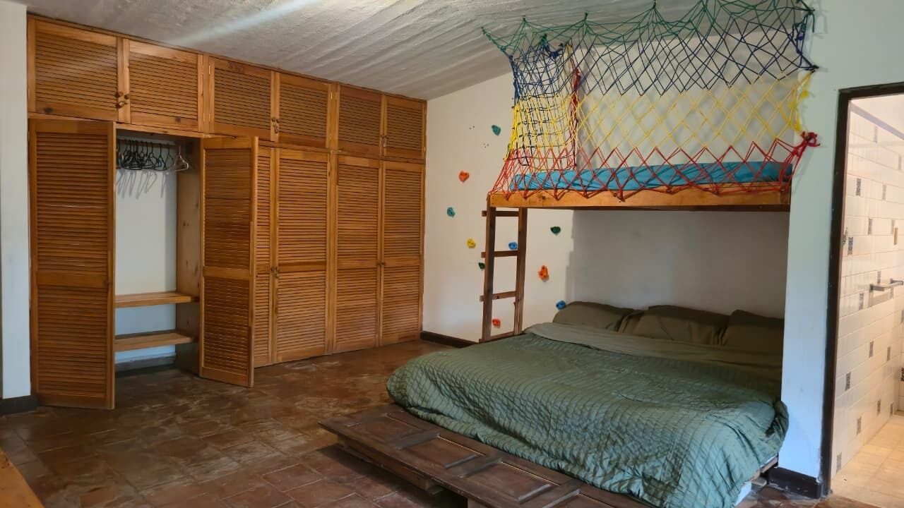Un dormitorio con literas, un armario de madera y una escalera.