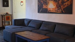 A sectional sofa with a wooden coffee table in a room with a painting on the wall.