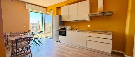 A modern kitchen with white cabinets, a stainless steel range hood, and a built-in oven.