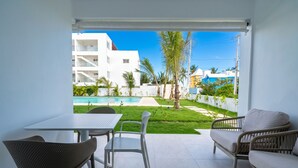 Eine Terrasse mit Tisch, Stühlen, einer Sitzecke und Blick auf ein Schwimmbad und Gebäude.