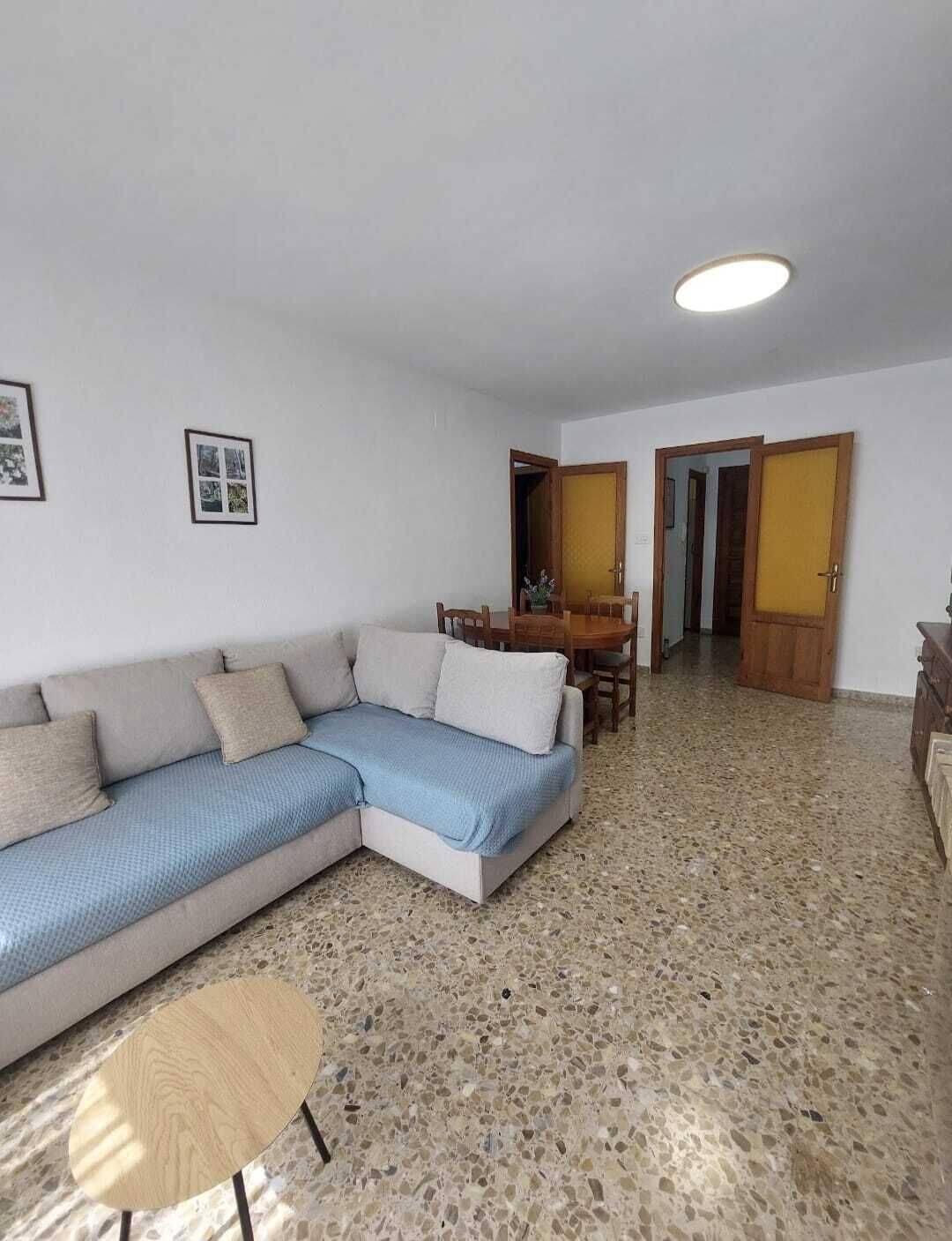 Una sala de estar con un sofá modular, una mesa de comedor y una pequeña mesa redonda.