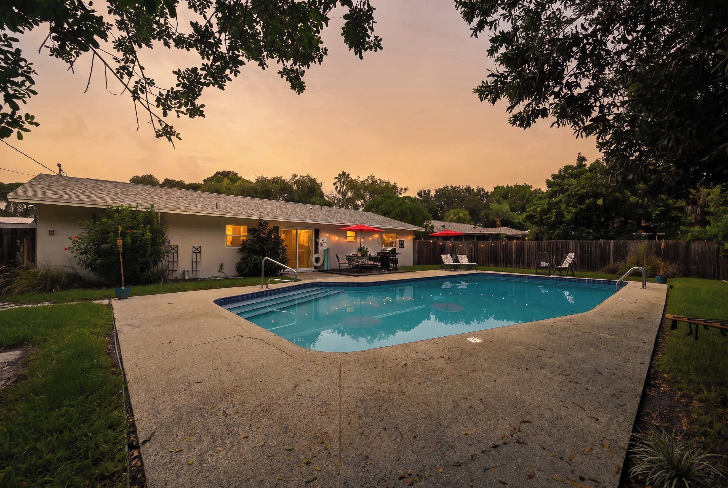 Un jardin avec une piscine, un patio couvert et une maison.