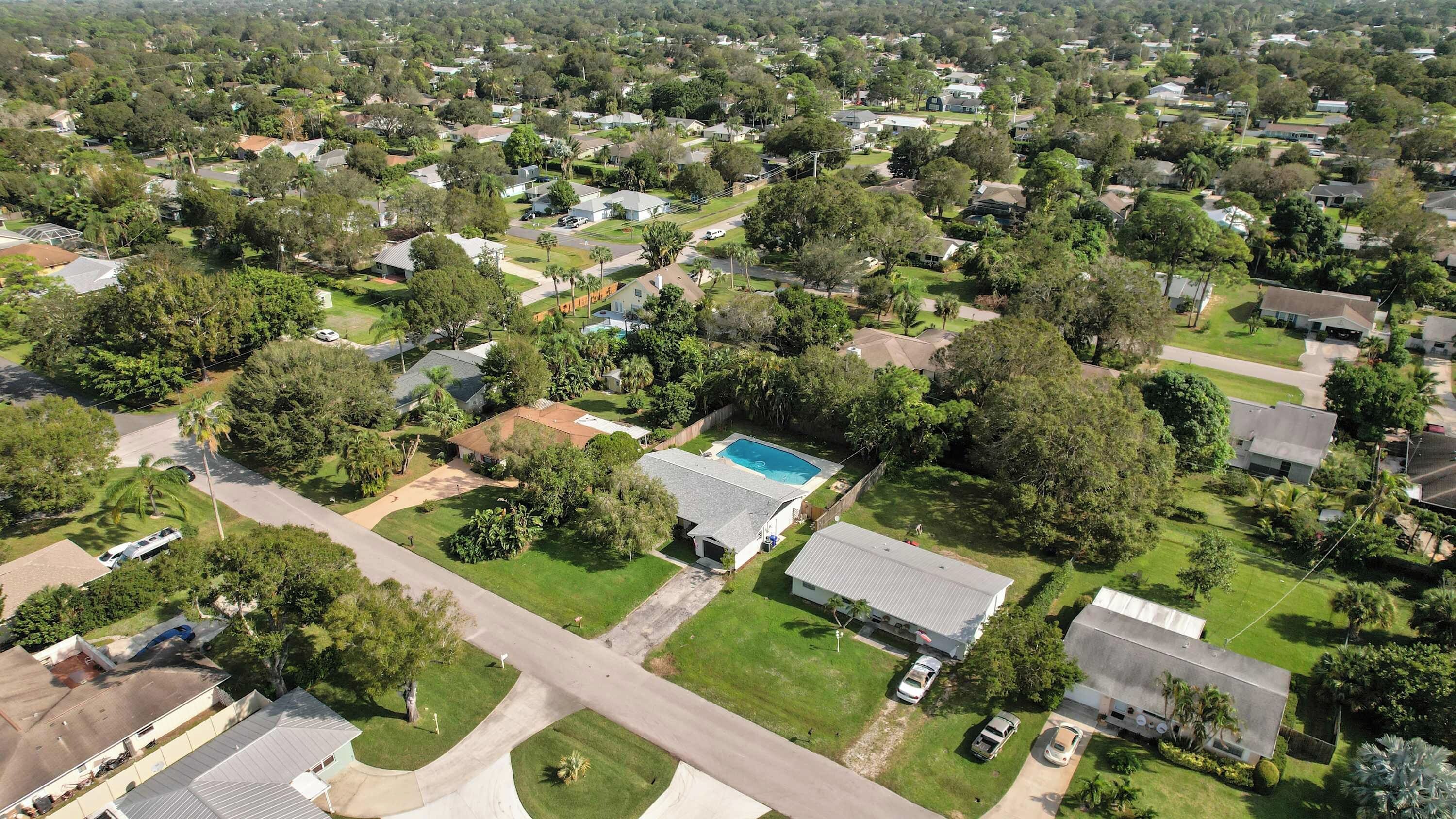 Un quartier résidentiel avec des maisons, une piscine et un grand bâtiment doté d’un toit plat.
