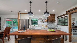 Una cocina moderna con una isla grande, electrodomésticos de acero inoxidable e iluminación colgante.