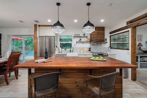 A modern kitchen with a large island, stainless steel appliances, and pendant lighting.