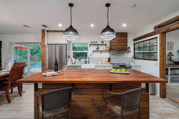 A modern kitchen with a large island, stainless steel appliances, and pendant lighting.