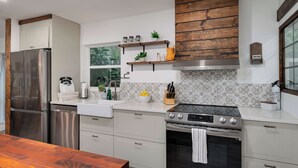 Una cocina moderna con electrodomésticos de acero inoxidable, armarios blancos y azulejos decorativos.