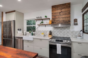 A modern kitchen with stainless steel appliances, white cabinetry, and decorative tiles.