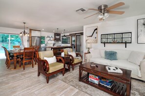 A spacious living area with a dining table, wooden chairs, a white sofa, and a coffee table.