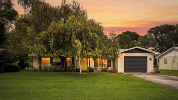A residential property with a well-maintained lawn, a garage, and a house with a yellow door.