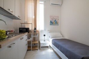 Ein kleines Schlafzimmer mit einem Einzelbett, einem Nachttisch und einem Beistelltisch.