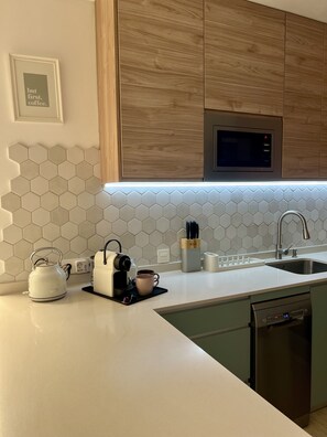 Een moderne keuken met een magnetron, waterkoker, koffiezetapparaat en een spoelbak.