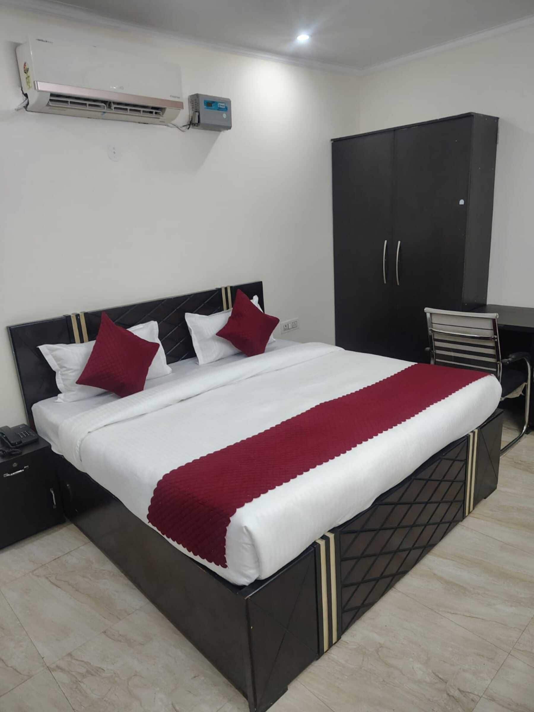 Habitació d'hotel amb un llit, un armari, una taula i aire condicionat.