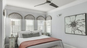 Una camera da letto con un letto, una ventola a soffitto e un'opera d'arte appesa al muro.