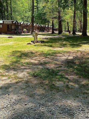 A campground with wooden cabins, a gravel path, and a grassy area. - Enjoyable 2-bedroom cabin in charming Cherokee with cool AC (Cherokee)