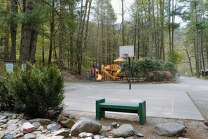 A playground with a basketball hoop, surrounded by trees and rocks. - Enjoyable 2-bedroom cabin in charming Cherokee with cool AC (Cherokee)