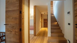 A wooden staircase leading to a bedroom with a bed and a bedside table.