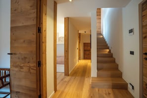 A wooden staircase leading to a bedroom with a bed and a bedside table.