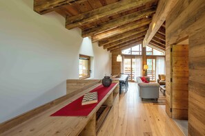 A spacious room with wooden beams, a long table with a chessboard, and a sofa.