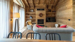 A cozy living room with a sofa, chairs, a fireplace, and a television.