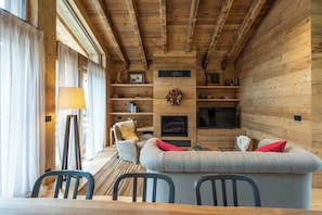 A cozy living room with a sofa, chairs, a fireplace, and a television.