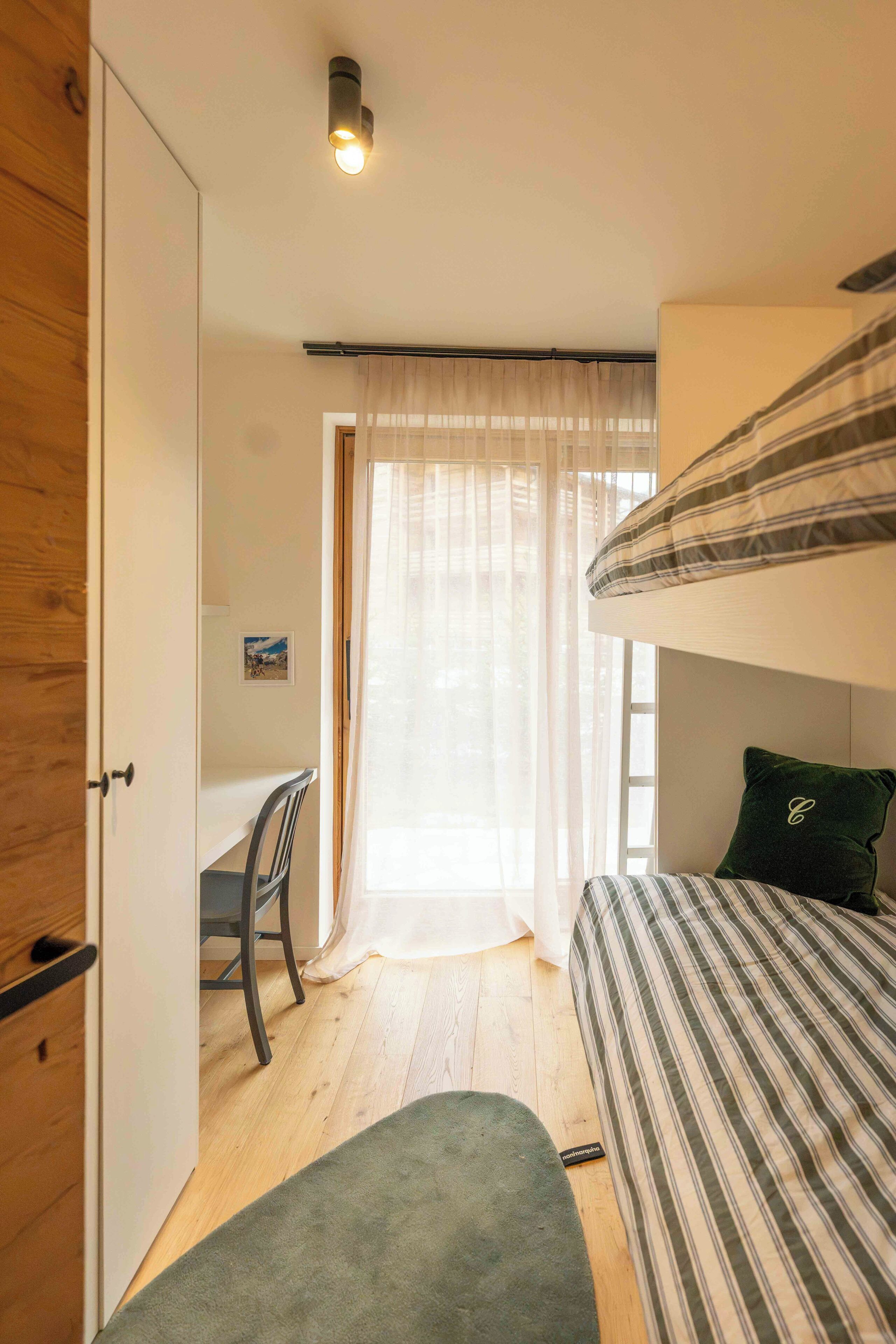 A room with a bunk bed, a desk, and a chair.