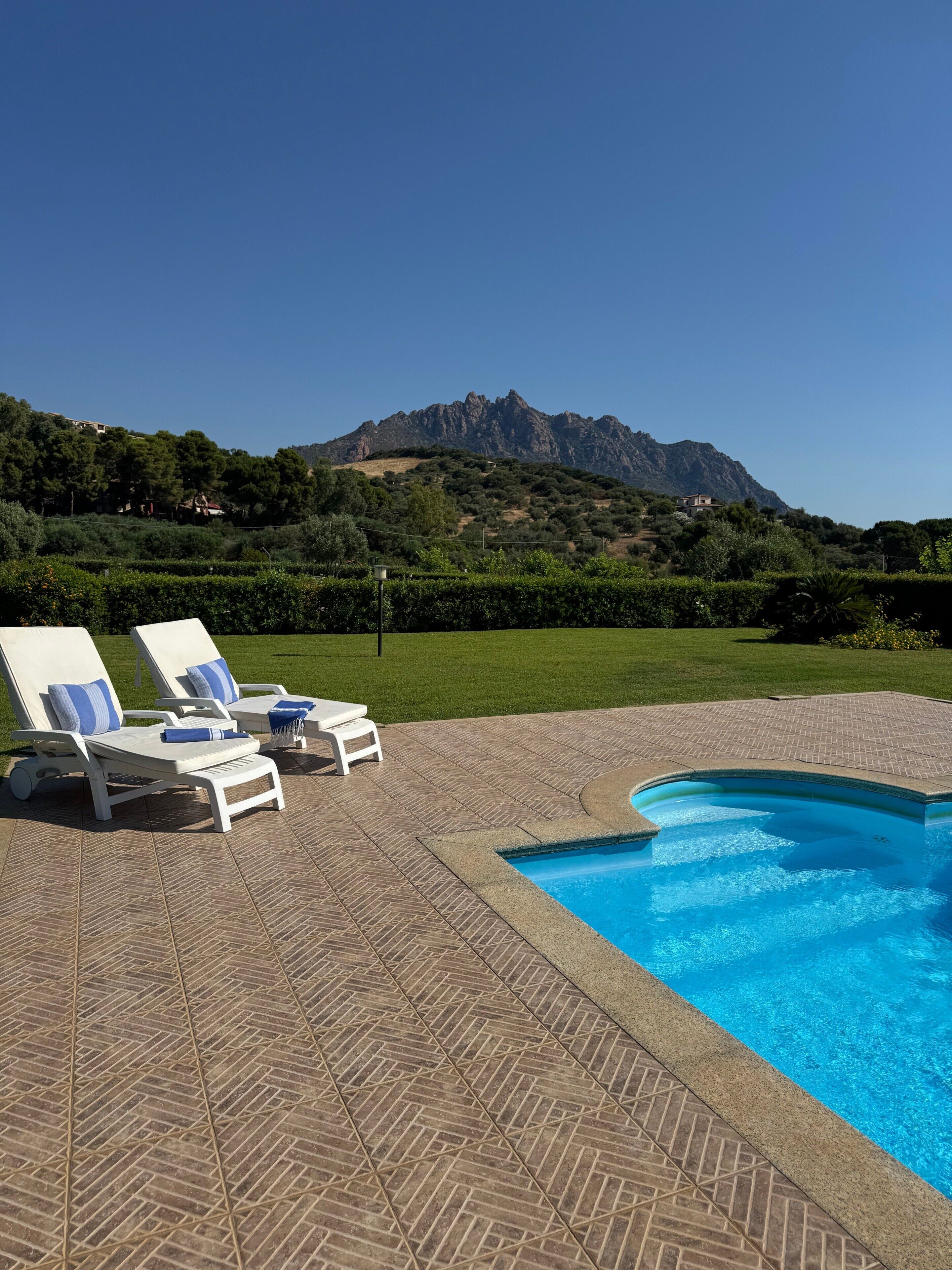 A swimming pool with lounge chairs and a view of a mountain.