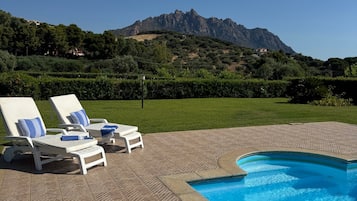 A swimming pool with lounge chairs and a view of a mountain.