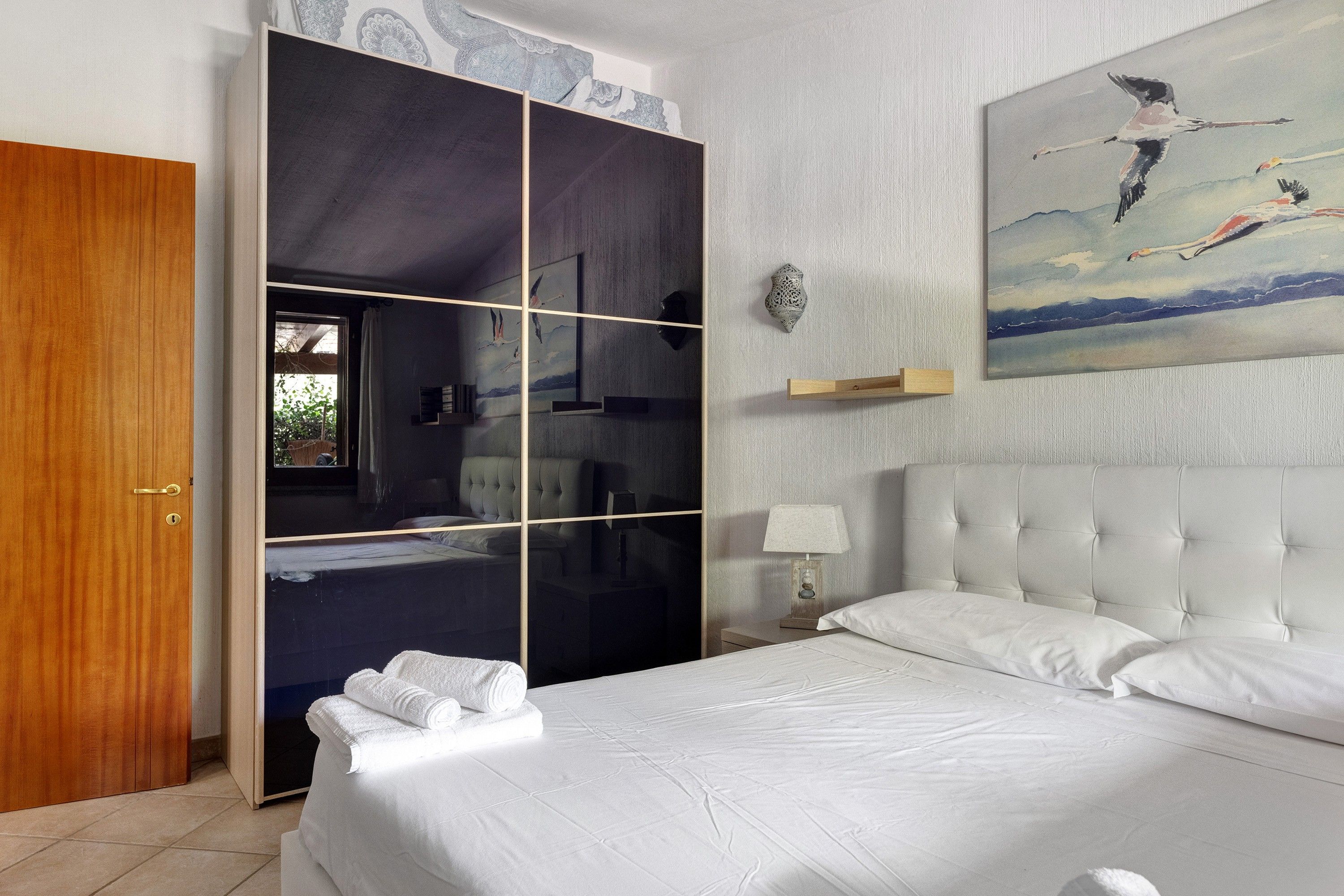 Une chambre d’hôtel avec un lit, une armoire, un tableau et une table de chevet.