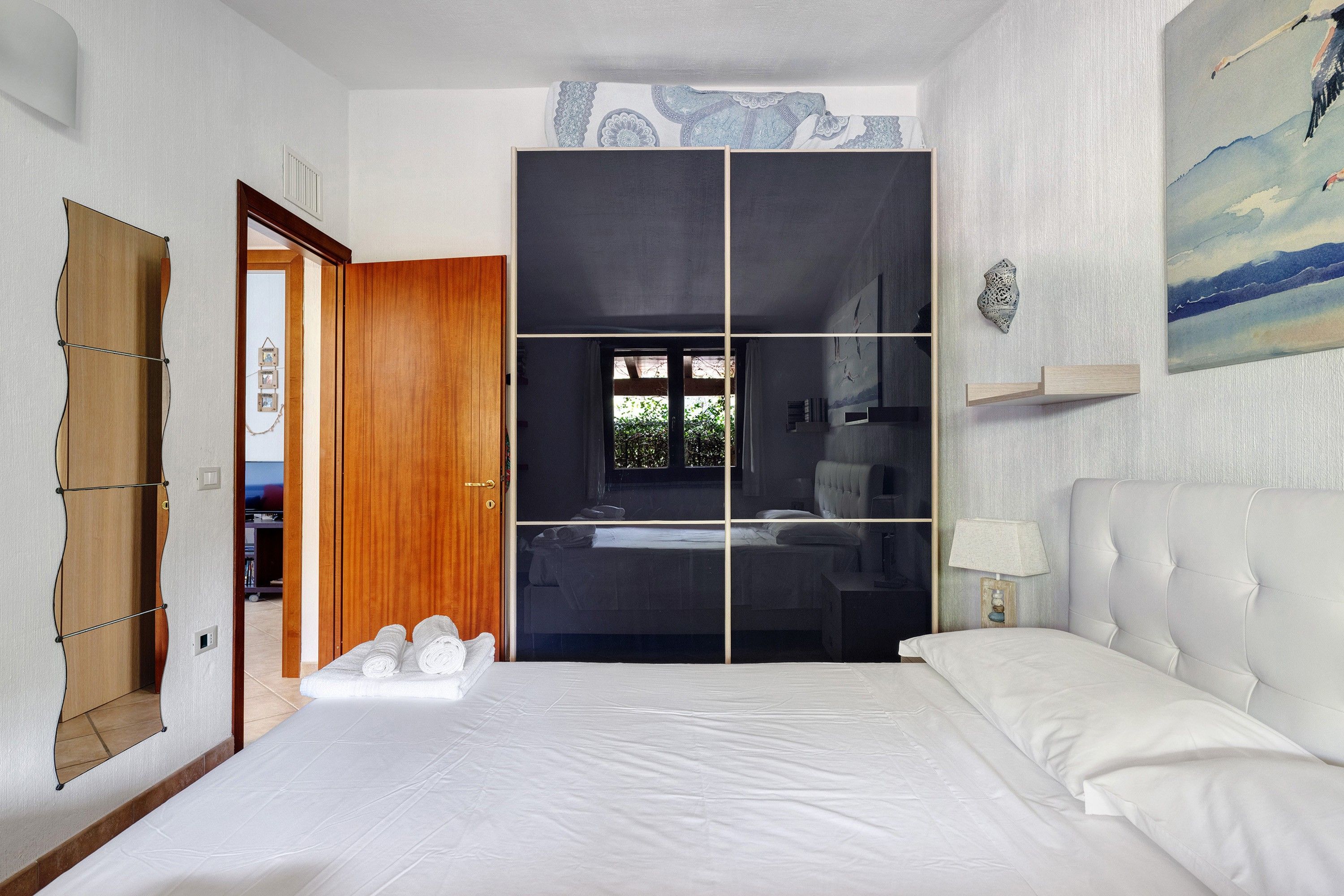 Une chambre à coucher avec un lit, une armoire et un tableau accroché au mur.