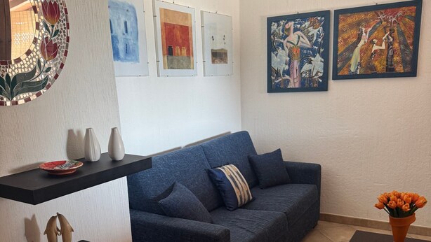 A living room with a blue sofa, a coffee table, and artwork on the walls.