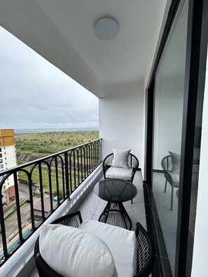 A balcony with a view of a distant landscape, a round table, and two chairs. - Traveler's Loft- Park views near JKIA&SGR with Pool & Gym (Nairobi)
